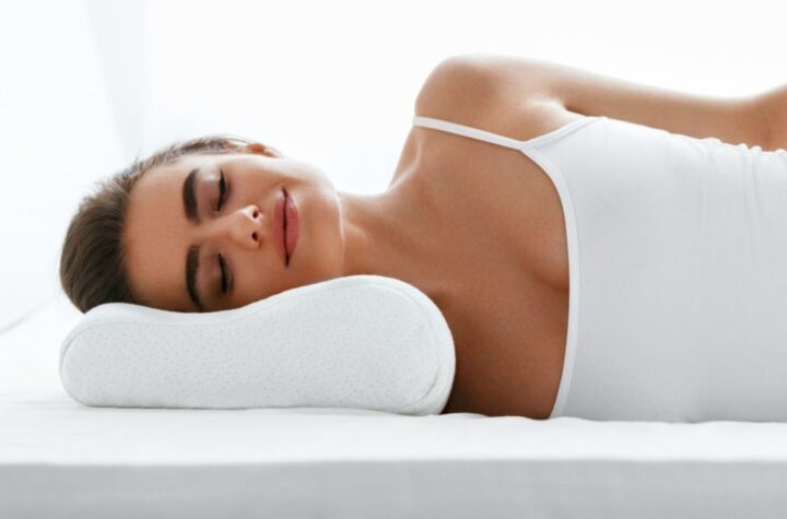 A woman peacefully resting on a bed, her head gently supported by a pillow specific for a better sleep quality